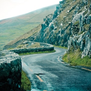 A narrow road winds through rocky hills in the Dingle Peninsula in Ireland.
