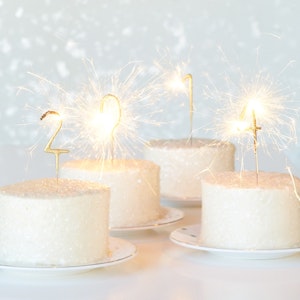 Sparkling candles spell out the new year on small cakes
