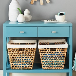 An entryway with a turquoise table holds baskets and incident items
