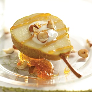 A roasted pear is served with vanilla yogurt, hazelnuts and a drizzled ginger-agave sauce.

