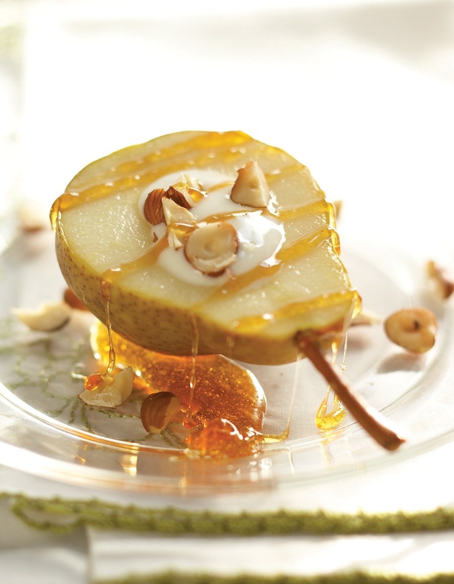 A roasted pear is served with vanilla yogurt, hazelnuts and a drizzled ginger-agave sauce.