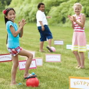 Three children play a game of Moses' Kickball Croquet outside.

